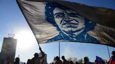 Un manifestante con una bandera con el rostro de Víctor Jara.