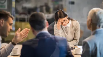quatro pessoas brancas em uma sala de reunião, um homem parece discutir e uma mulher parece chateada