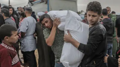 Jóvenes palestinos cargando un saco de alimentos dado por la UNRWA