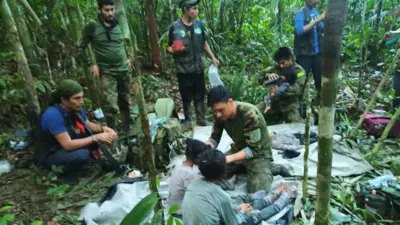Agentes com fardas camufladas cuidando de crianças no meio da floresta