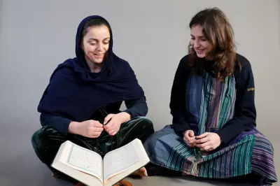 دو زن با حجاب و بی‌حجاب مقابل قرآن نشسته‌اند