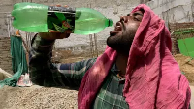 Homem bebe água no calor da Índia