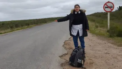 Mulher de pele clara pede carona em estrada rural
