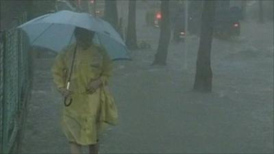 Woman with umbrella walking down flooded street