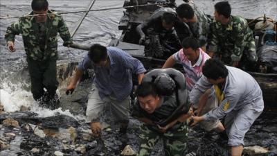 Clean-up workers drenched in oil