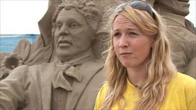 Sand sculptor with example of her work