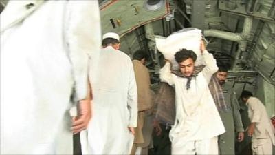 Relief workers unload food from a helicopter