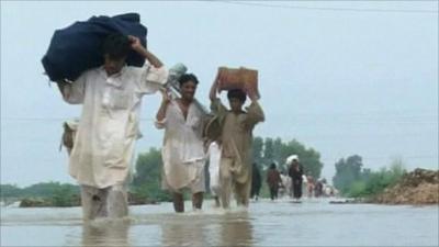 Men carrying belongings on back through floodwater