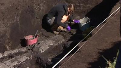 An archaeologist excavates the site