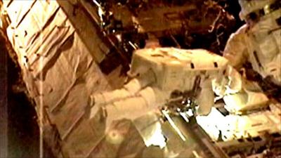 An astronaut attempts to fix the cooling unit on the ISS