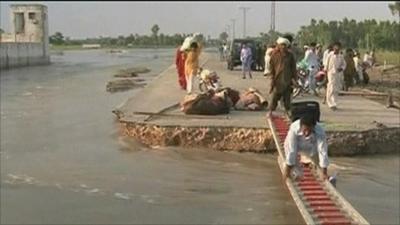 A man uses a ladder to cross flood waters