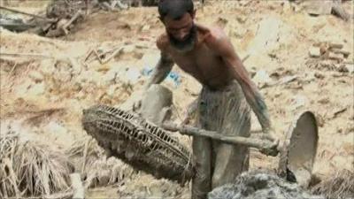 Pakistani man lifting mud-coated fan