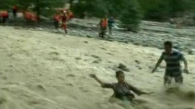 A reporter is swept away by the flood water