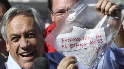 Chile's President Sebastian Pinera holds up a plastic bag containing a message, from miners trapped in a collapsed mine