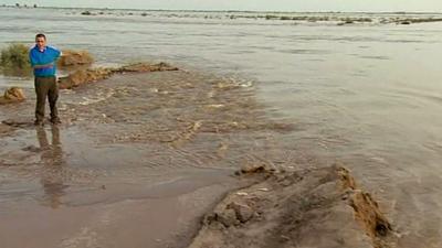 Chris Morris standing next to breached flood defences near Shahdadkot