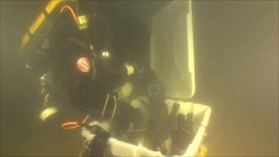 A diver puts the beer bottles in a container