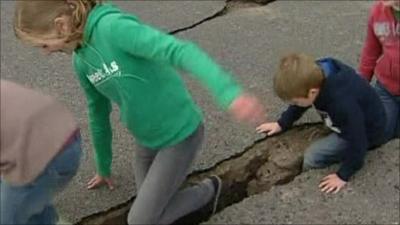 Children walk through crack in road