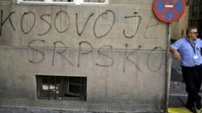 Man standing beside graffiti saying "Kosovo is Serbian" in Belgrade