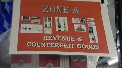 Sign on shelves fuill of counterfeit goods