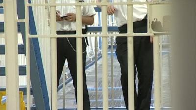 Prison wardens behind a barred gate