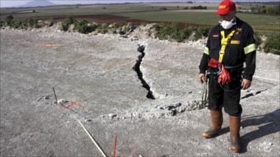 Worker stands next to crack