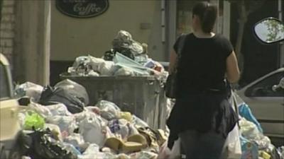 Woman walks past pile of rubbish