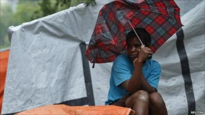 Woman sheltering under broken umbrella