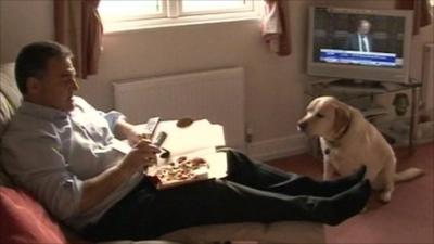 A man eating pizza in front of the television