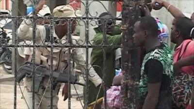 A guard stops crowds of people at the border