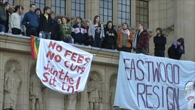 Students protesting on the balcony of a university building with banners