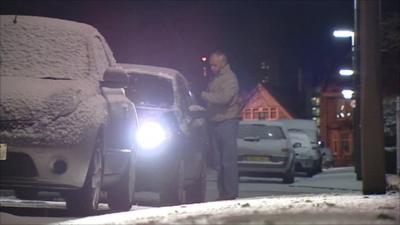 Man clearing his car from snow