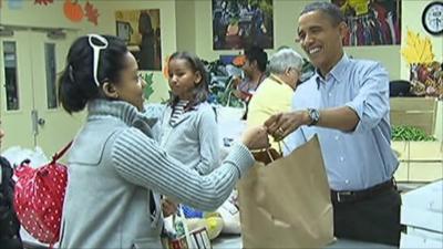 Obama hands a bag of food to a woman