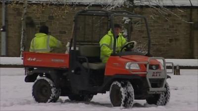 Men spread grit from a vehicle