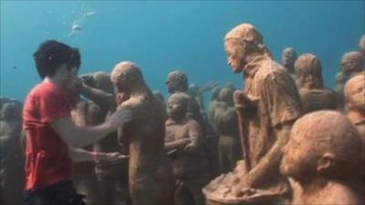 Greenpeace activist underwater with human sculptures