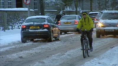 Cars and a cyclist on a snow covered road in Aberdeen