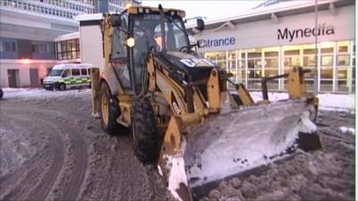 Tractor clearing snow from the front of a hospital