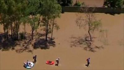 People wading through floodwater in Queensland