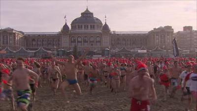 The swimmers run towards the icy waters