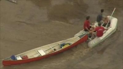 People towing a boat with a dighy through flood water