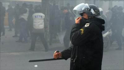 A Tunisian policeman covers his face as riot police fire tear gas during a protest