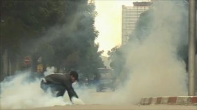 Protestor trying to pick up tear gas canister