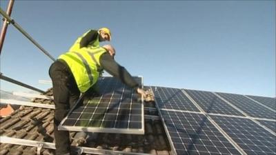 Men installing solar panels to a roof