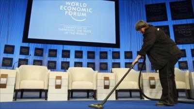 A cleaner vacuums the platform of the main meeting hall at the World Economic Forum in Davos, Switzerland