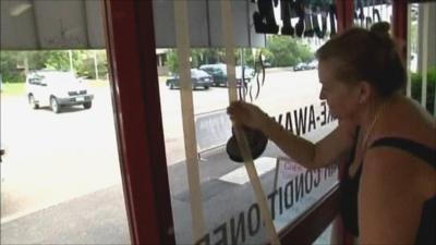 Woman taping up shop windows in Queensland