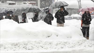 Passengers wait for a bus in the snow in Gangneung City, South Korea