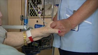 A nurse holds an elderly patient's hand