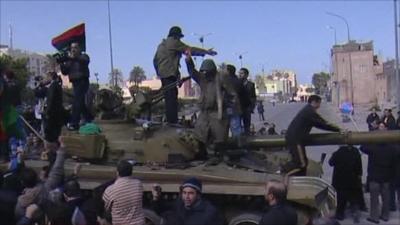 Protesters climb on tank
