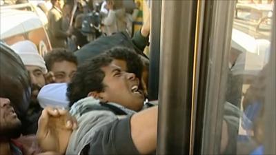 Refugees fight to get onto a bus