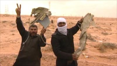 Rebels hold wreckage from a fighter bomber from Colonel Gaddafi's airforce