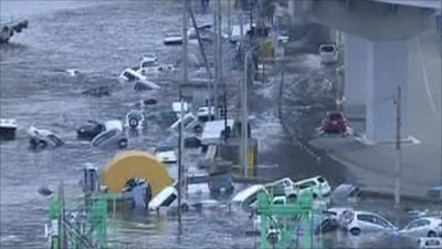 A wave surge sweeps away cars in Japan